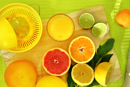 Slices of citrus fruit and a fresh juice on a wooden tray