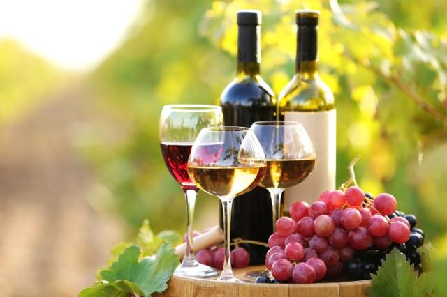 Tasty wine on wooden barrel on grape plantation background