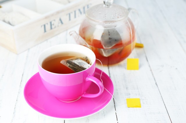 BM_Cup of tea, teapot and tea bags on wooden table close-up_70658662